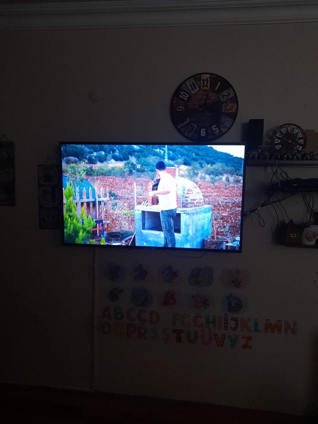 Duvara monte edilmiş televizyonda film izleniyor